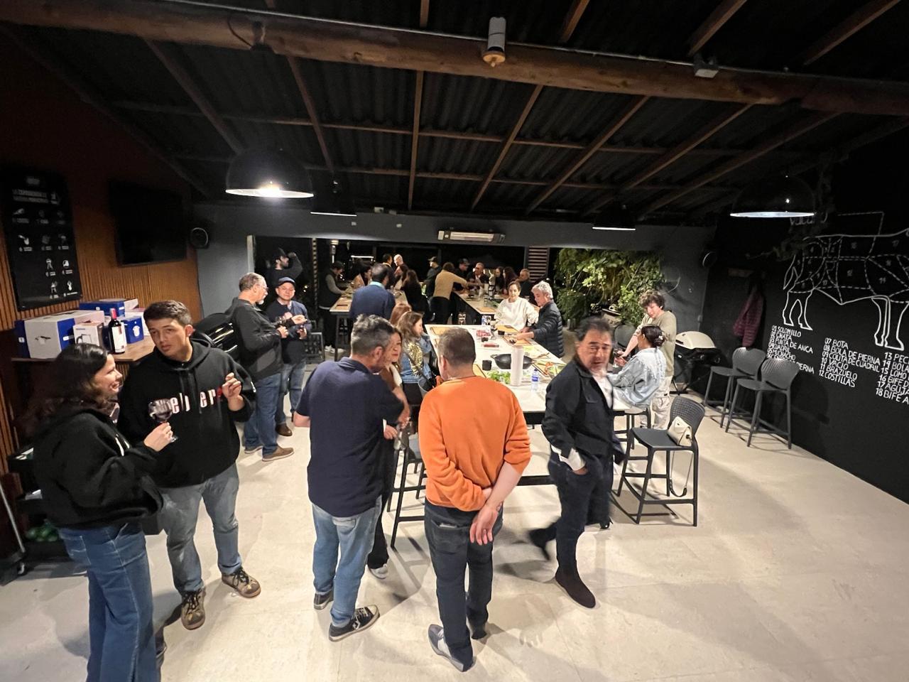 Integrantes de la empresa conversando con copa en mano durante el taller de parrilla