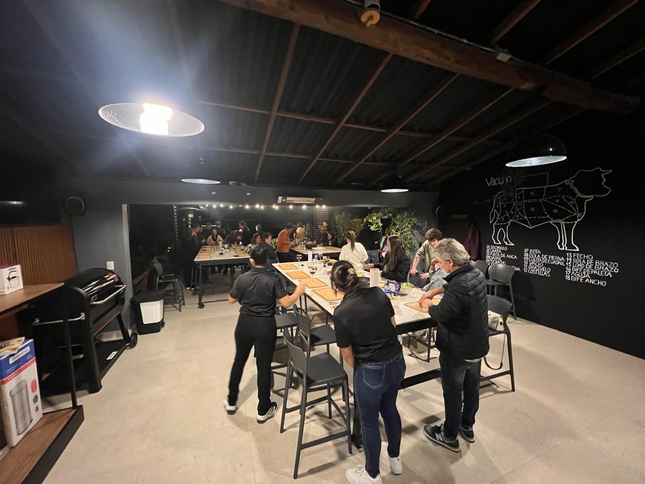 Taller nocturno de parrilla con equipos trabajando en estaciones de corte