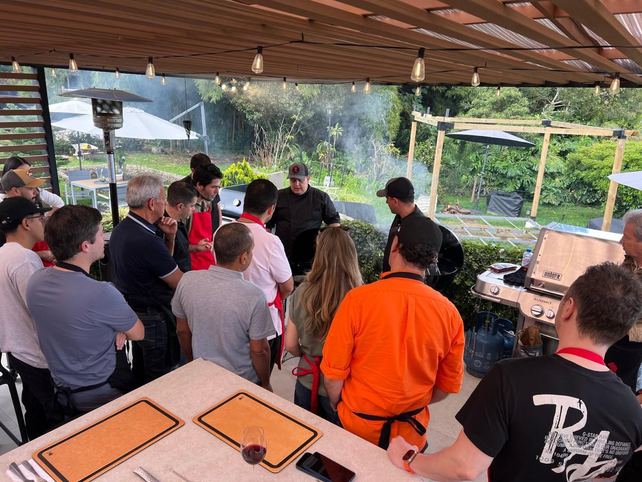 Instructor de Llamas y Legado explicando técnicas de parrilla a un grupo empresarial